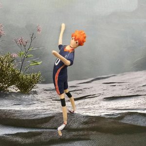 Boneco de pano do Hinata, de Haikyuu!!, de camisa nº 10, em pose de salto sobre uma pedra