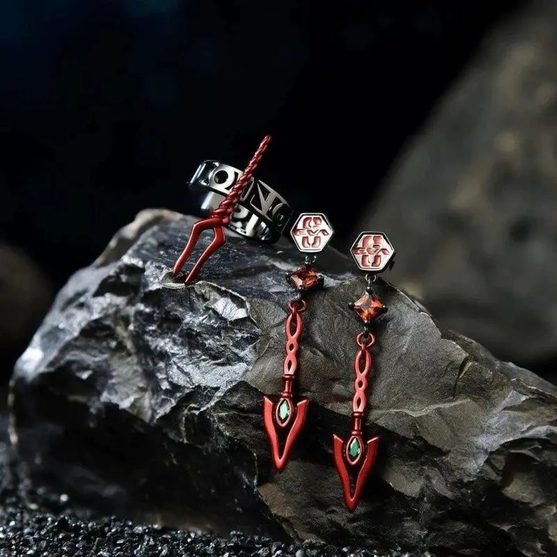 Brincos de lança vermelha e ear cuff prateado de Evangelion sobre uma pedra escura