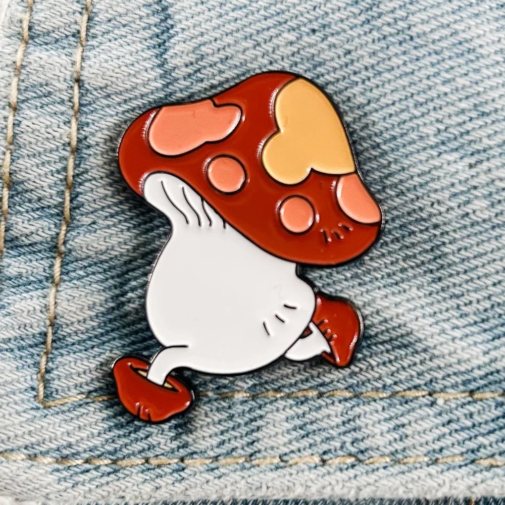Pin de esmalte do cogumelo andante de Dungeon Meshi, com chapéu vermelho e pintas, preso em jaqueta jeans