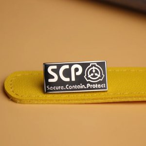 Broche esmaltado preto e branco com o logotipo da SCP Foundation sobre superfície amarela