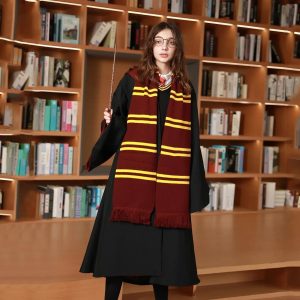 Mulher com cachecol listrado de vermelho e dourado e capa preta em frente a uma estante de livros, estilo Hogwarts