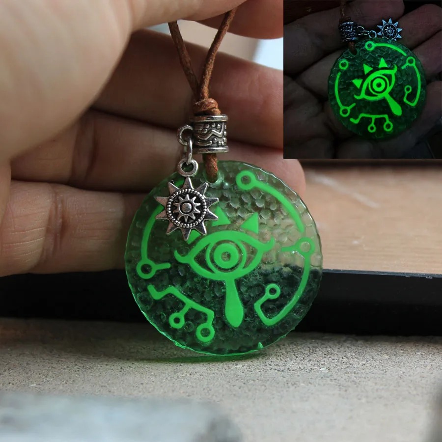 Colar com pingente do Olho Sheikah de The Legend of Zelda em cordão marrom, com brilho verde no canto