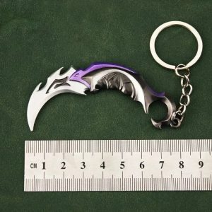 Chaveiro de metal em forma da karambit Reaver do Valorant, com argola, ao lado de uma régua de 9 cm