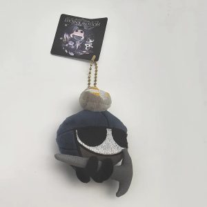 Pelúcia pequena do Zote, de Hollow Knight, com capacete azul e capa cinza, pendurada em corrente de bolinhas