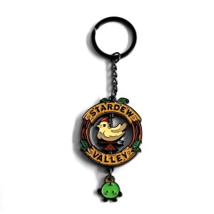 Chaveiro de metal de Stardew Valley com placa redonda, galinha giratória e Junimo verde pendurado, sobre fundo branco