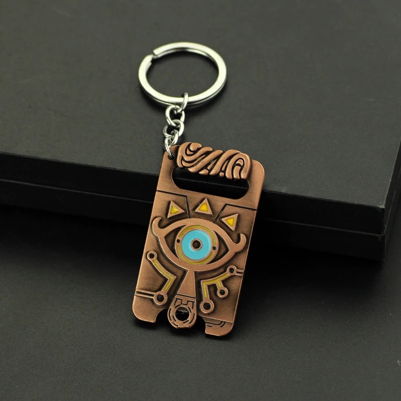 Chaveiro do Purah Pad de Zelda sobre superfície preta, com argola de metal