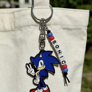Chaveiro de metal do Sonic com contas que formam o nome SONIC, preso em uma bolsa de pano