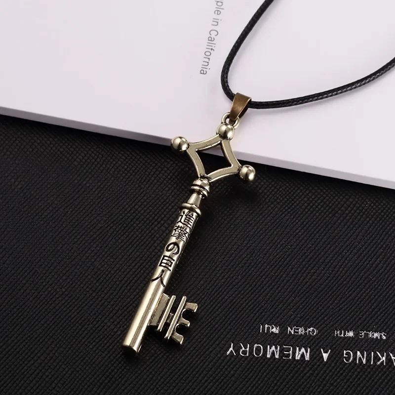 Colar com a chave do Eren em acabamento dourado antigo sobre fundo escuro