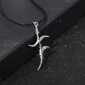 Colar com pingente da adaga Faca Negra de Elden Ring, em metal prateado, sobre fundo escuro