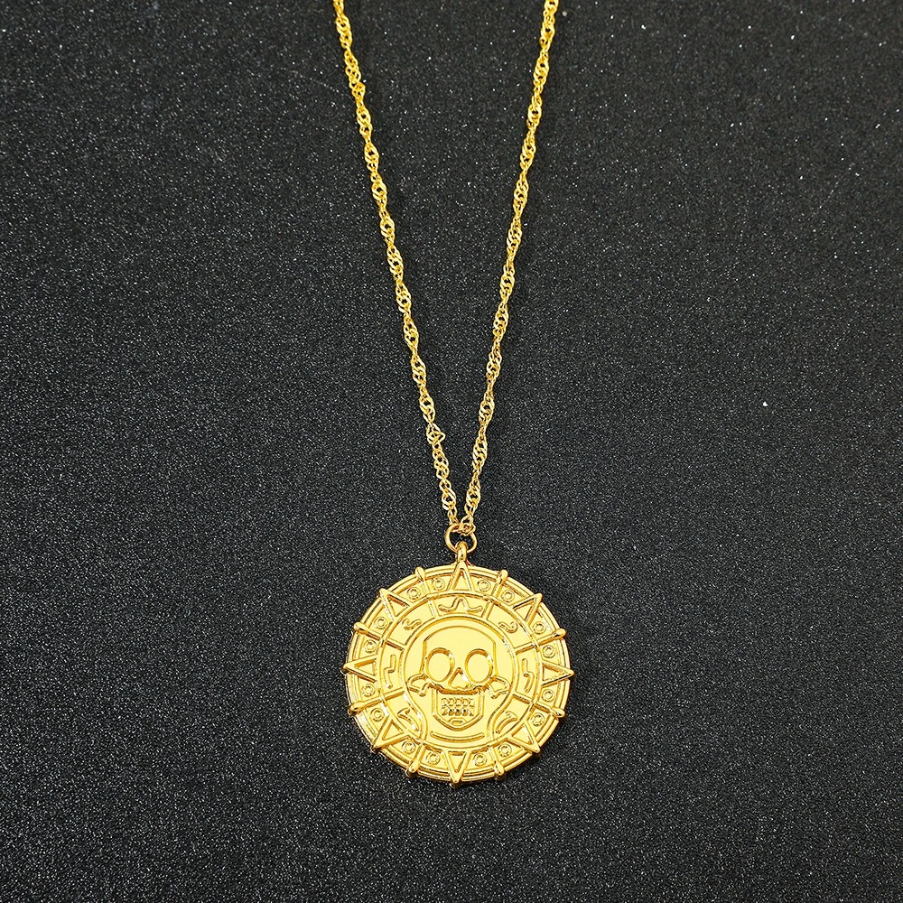 Medalhão dourado com caveira pendurado em corrente fina sobre fundo escuro, Piratas do Caribe