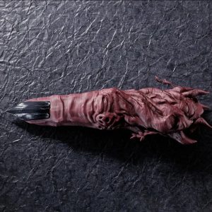 Dedo do Sukuna, de Jujutsu Kaisen, em PVC vermelho arroxeado com unha escura, sobre fundo cinza