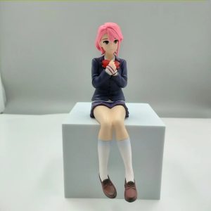 Figure da Aira Shiratori, de Dandadan, sentada de uniforme escolar azul sobre um bloco branco