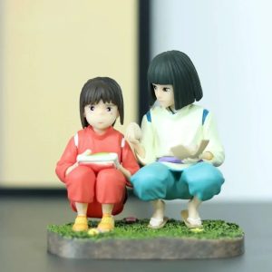 Figure da Chihiro e do Haku sentados lado a lado sobre base com grama, de A Viagem de Chihiro