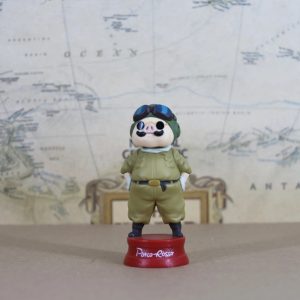 Figure do Porco Rosso de uniforme verde-oliva, capacete e óculos, em base vermelha, de Porco Rosso