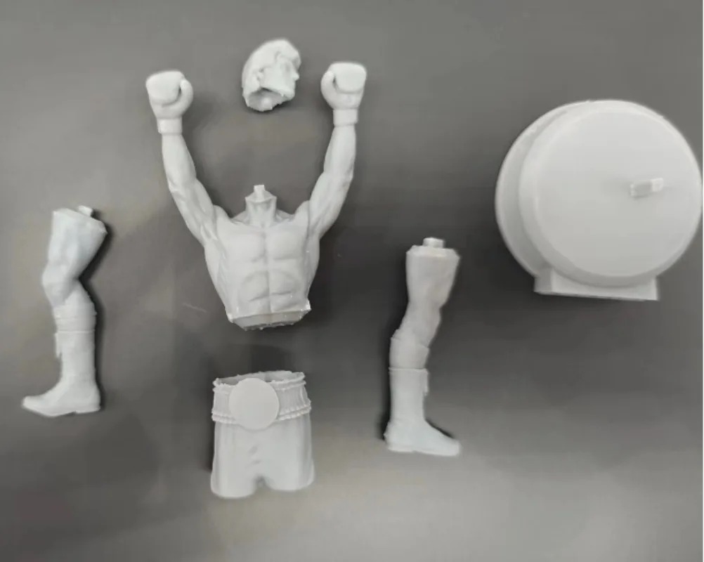 Peças em resina cinza claro do kit do Rocky Balboa: tronco, pernas, calção, cabeça e base