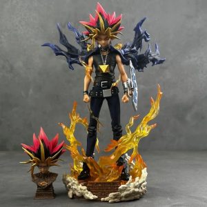Estátua do Yugi Muto de Yu-Gi-Oh! sobre base com chamas, com capa azul e disco de duelo, e a cabeça extra ao lado