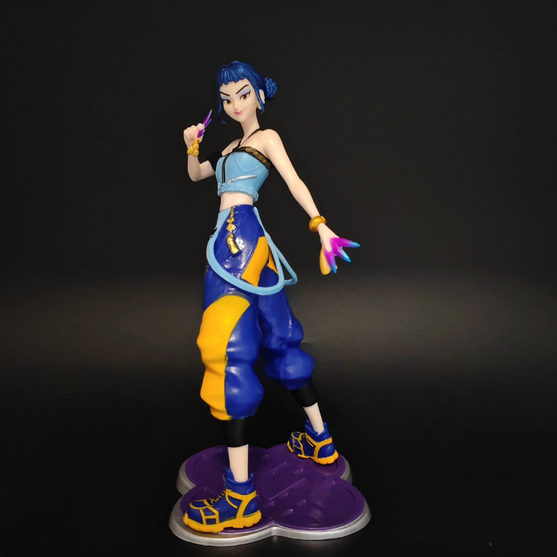 Figure da Zoey, de Guerreiras do K-Pop, de cabelo azul, regata azul e calça larga azul e amarela, sobre base roxa
