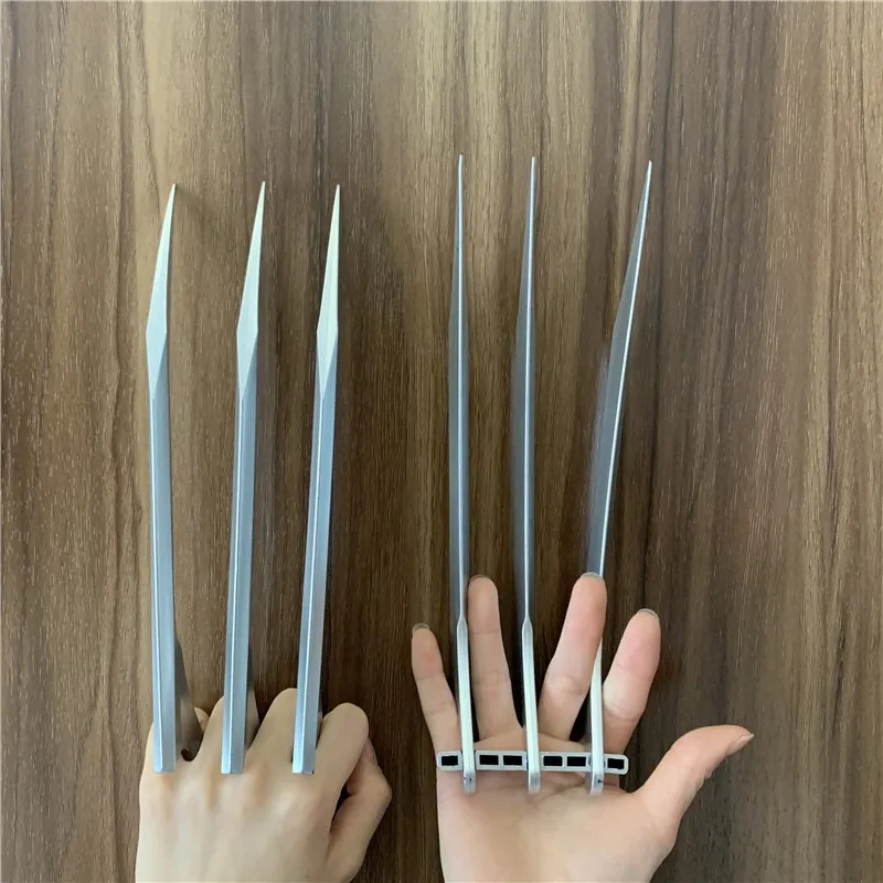 Garras prateadas de plástico presas aos dedos de uma mão, ao lado da outra mão aberta