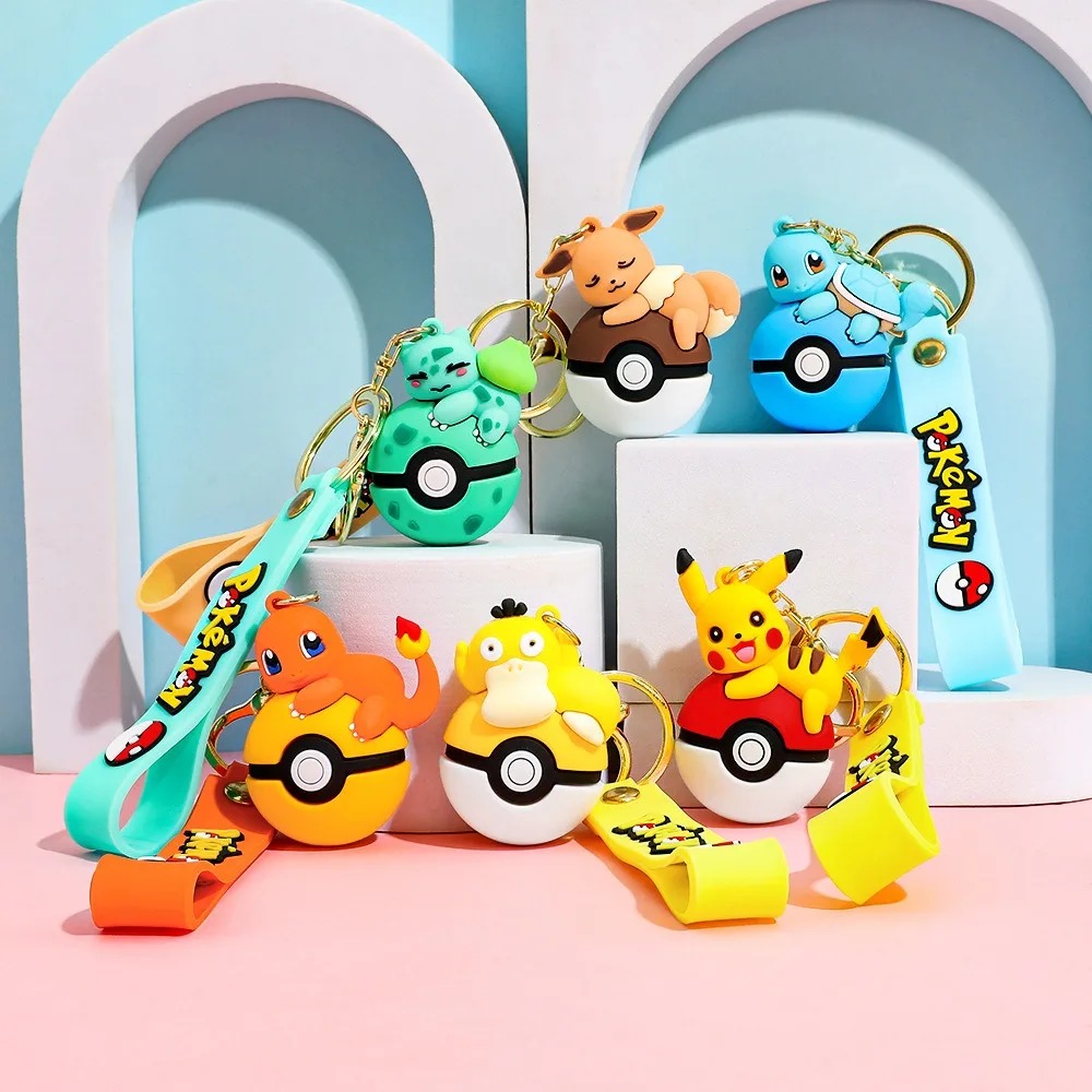 Seis chaveiros de Pokémon sobre Pokébolas, com alças coloridas, em cenário azul e rosa