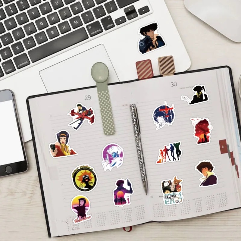 Adesivos de Cowboy Bebop colados em um caderno ao lado de um notebook