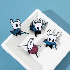 Quatro broches esmaltados de Hollow Knight com o Cavaleiro e a Hornet sobre fundo azul
