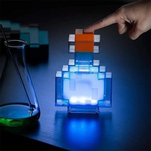 Luminária em formato de frasco de poção do Minecraft acesa em azul, com a mão tocando a tampa