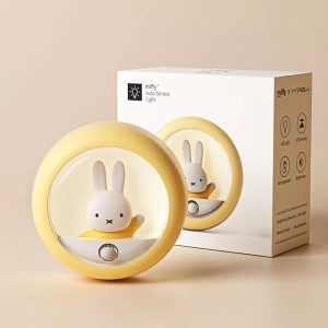 Luminária redonda amarela com a coelhinha Miffy dentro, ao lado da caixa da embalagem