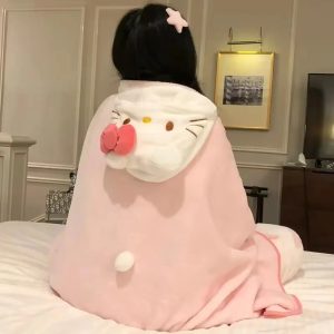 Pessoa de costas com a manta rosa de capuz da Hello Kitty, com laço rosa e pompom, sentada em uma cama