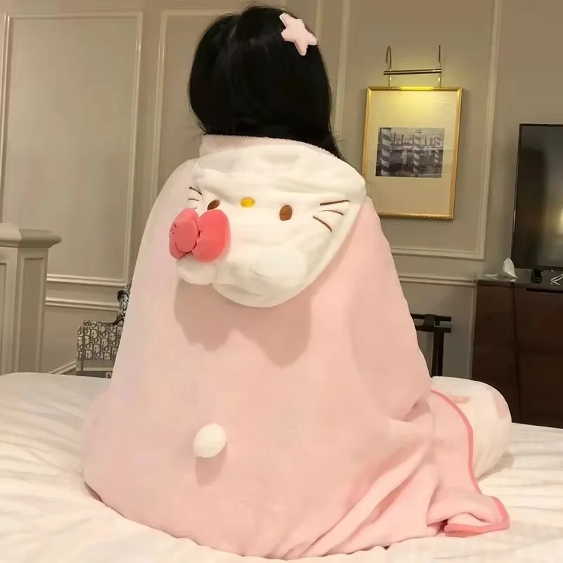 Pessoa de costas com a manta rosa de capuz da Hello Kitty, com laço rosa e pompom, sentada em uma cama