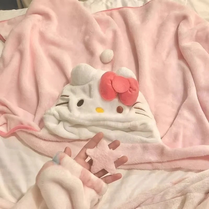 Manta rosa com capuz da Hello Kitty aberta sobre a cama, com o rosto e o laço rosa