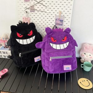 Duas mochilas de pelúcia do Gengar, de Pokémon, uma preta e uma roxa, sobre uma mesa