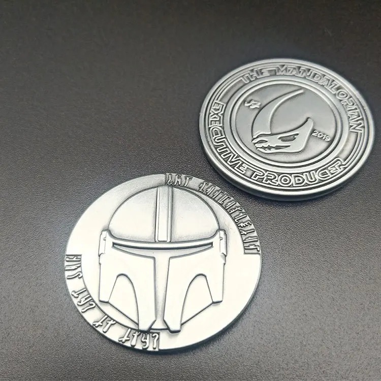 Moeda de metal com o capacete mandaloriano em relevo, acabamento prateado envelhecido, Star Wars