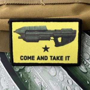 Patch amarelo de Halo com o rifle de assalto e a frase Come and Take It, preso em uma mochila bege