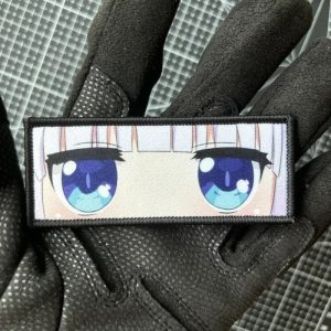 Patch retangular com os olhos azuis da Kanna Kamui, de Dragon Maid, segurado em luva preta