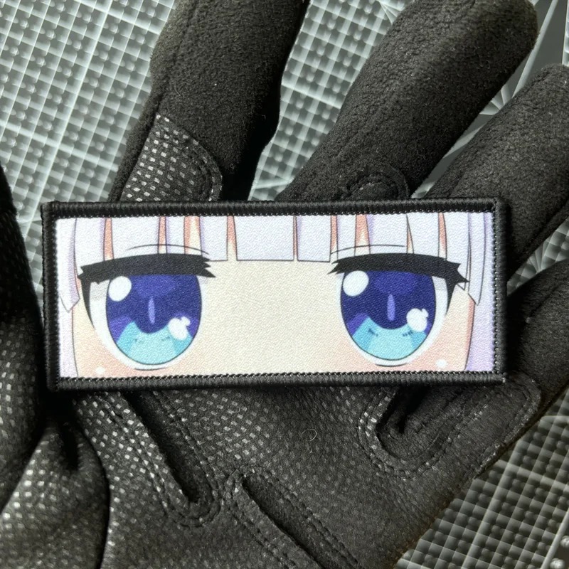 Patch retangular com os olhos azuis da Kanna Kamui, de Dragon Maid, segurado em luva preta