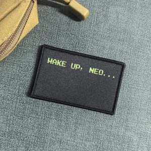 Patch retangular preto com a frase Wake up, Neo... em verde, de Matrix, sobre fundo cinza