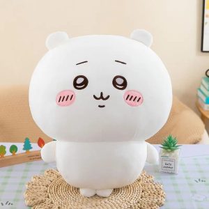 Pelúcia do Chiikawa, personagem branco e redondo com bochechas rosa, sentada sobre um apoio de palha