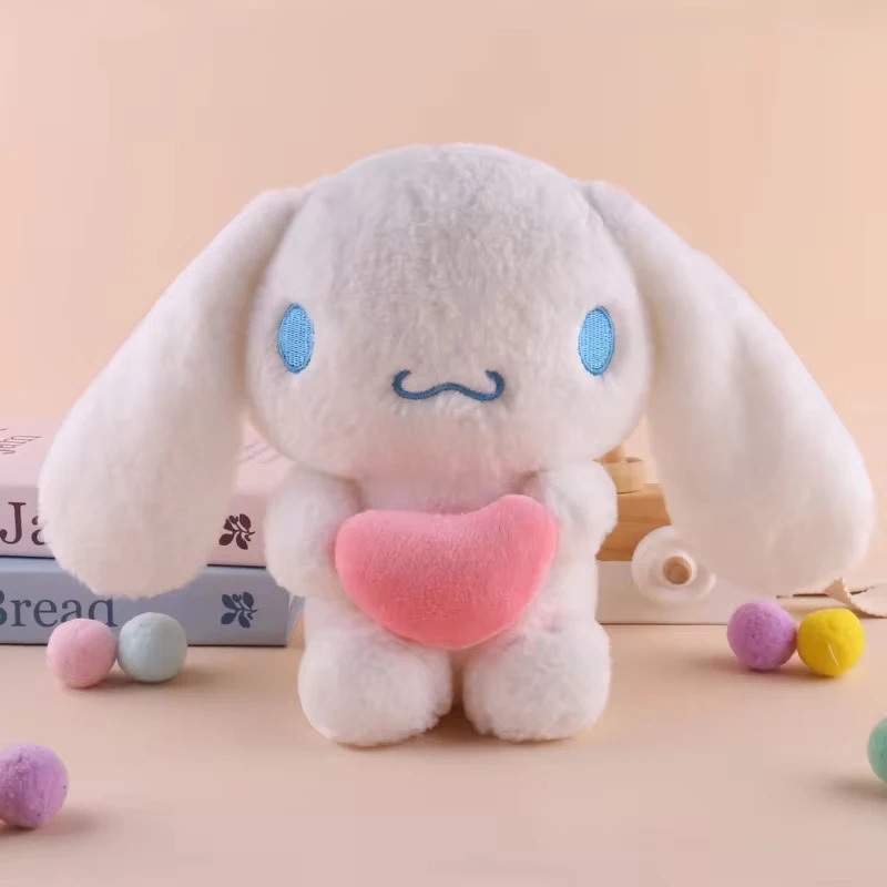 Pelúcia do Cinnamoroll branca de orelhas longas e olhos azuis, segurando um coração rosa