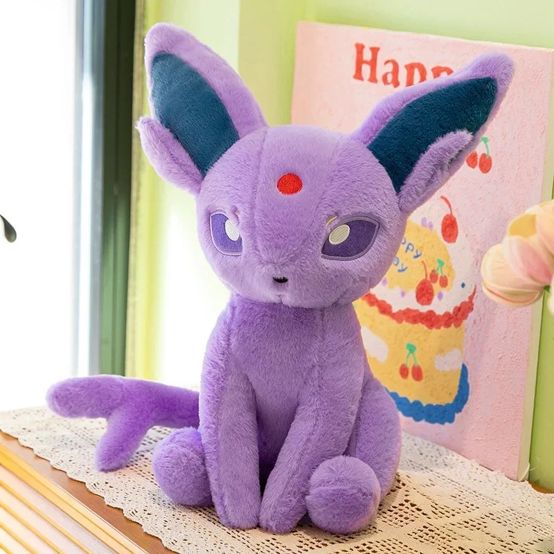 Pelúcia do Espeon, de Pokémon, lilás, sentada, com orelhas azuis e joia vermelha na testa