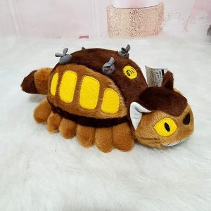Pelúcia do Gatobus de Meu Amigo Totoro sobre manta branca, vista lateral com janelas amarelas e ratinhos