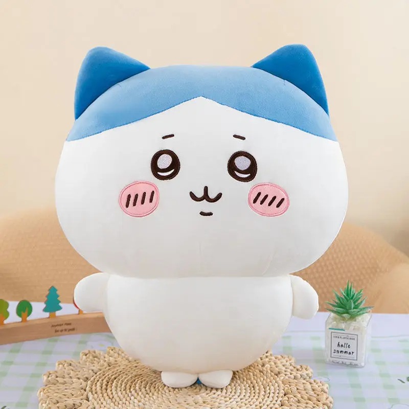 Pelúcia do Hachiware, de Chiikawa, sentada sobre um tapete de palha: gatinho branco com capuz azul e bochechas rosadas