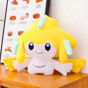 Pelúcia do Jirachi, de Pokémon, amarela e branca, com tiras azuis-claras, sentada sobre uma mesa