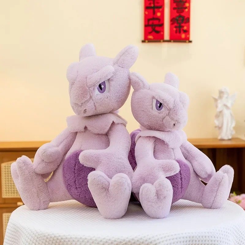 Duas pelúcias do Mewtwo sentadas lado a lado sobre uma mesa