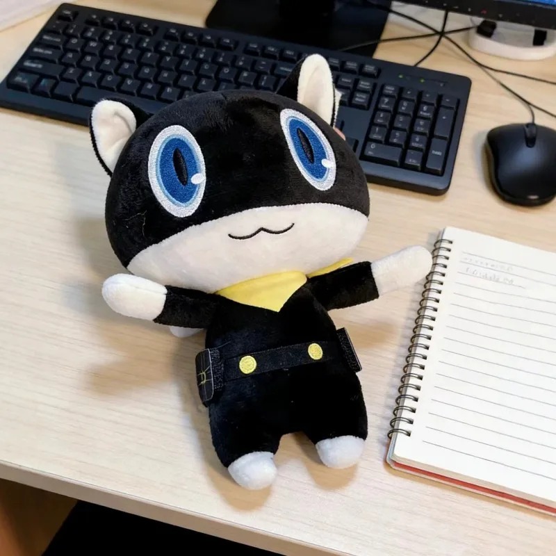 Pelúcia da Morgana, de Persona 5, sentada sobre uma mesa ao lado de um caderno