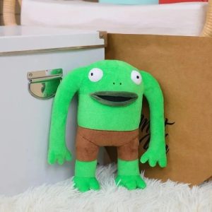 Pelúcia do Mr. Frog, de Smiling Friends, sapo verde de olhos grandes e short marrom, em pé sobre pelo branco