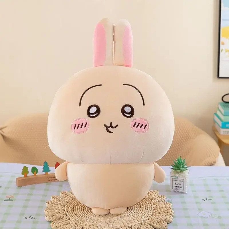 Pelúcia do Usagi, coelhinho de pelo bege e orelhas rosa de Chiikawa, sentado sobre um apoio de palha