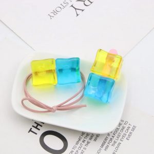 Elástico e presilha de cabelo com cubos translúcidos azul e amarelo da Bocchi, sobre prato branco