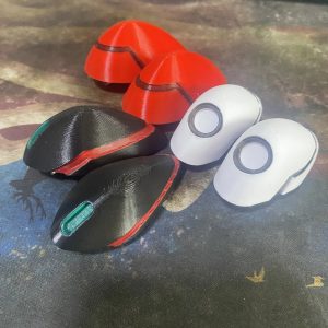 Presilhas de cosplay de Evangelion nas cores vermelha, branca e preta sobre uma mesa