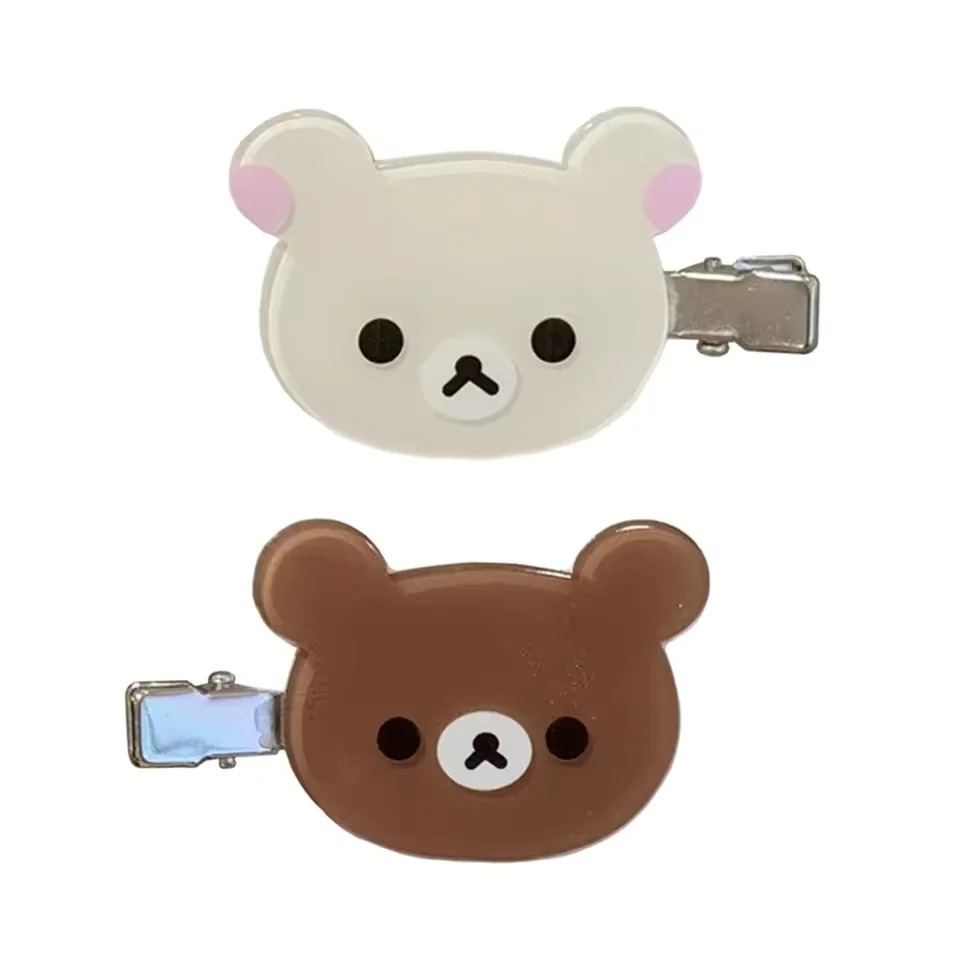 Presilhas do Rilakkuma, marrom, e da Korilakkuma, bege, com grampo de metal, sobre fundo branco