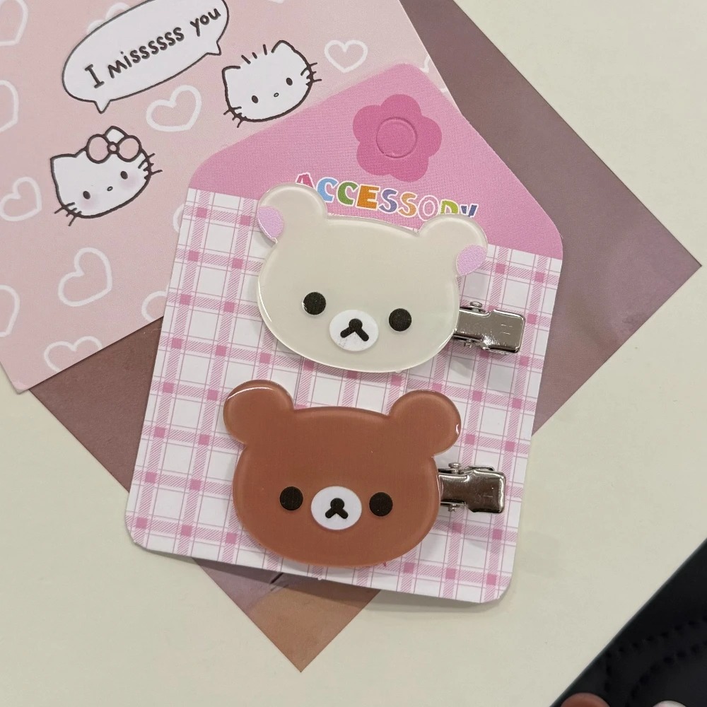 Presilhas do Rilakkuma e da Korilakkuma presas em cartela rosa quadriculada